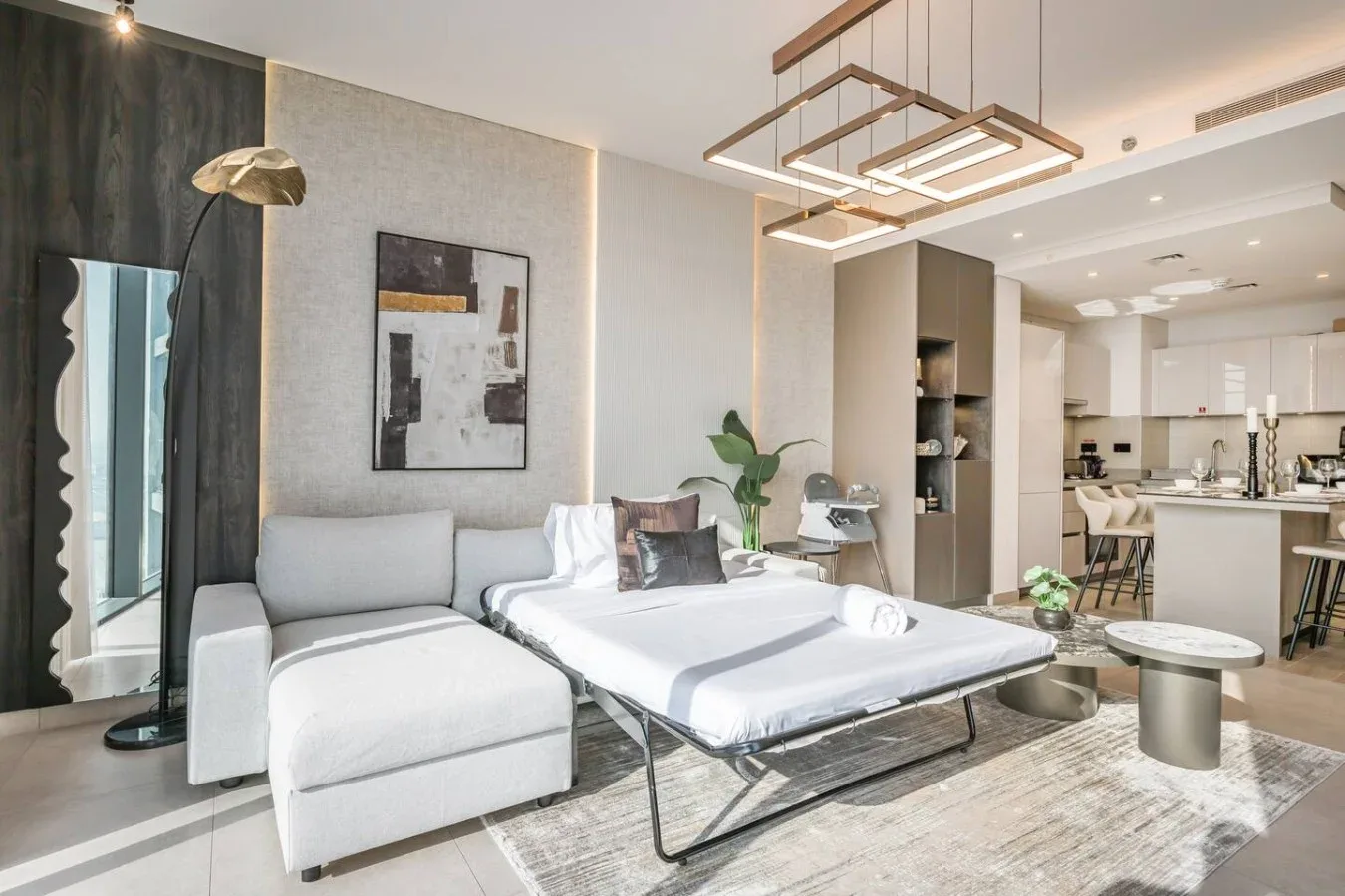Sala de estar moderna y abierta, con un sofá, una cama y la cocina al fondo.