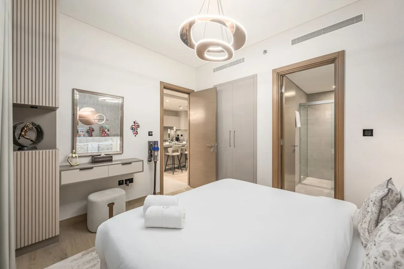 Un dormitorio luminoso con una cama grande, un tocador y una puerta abierta.