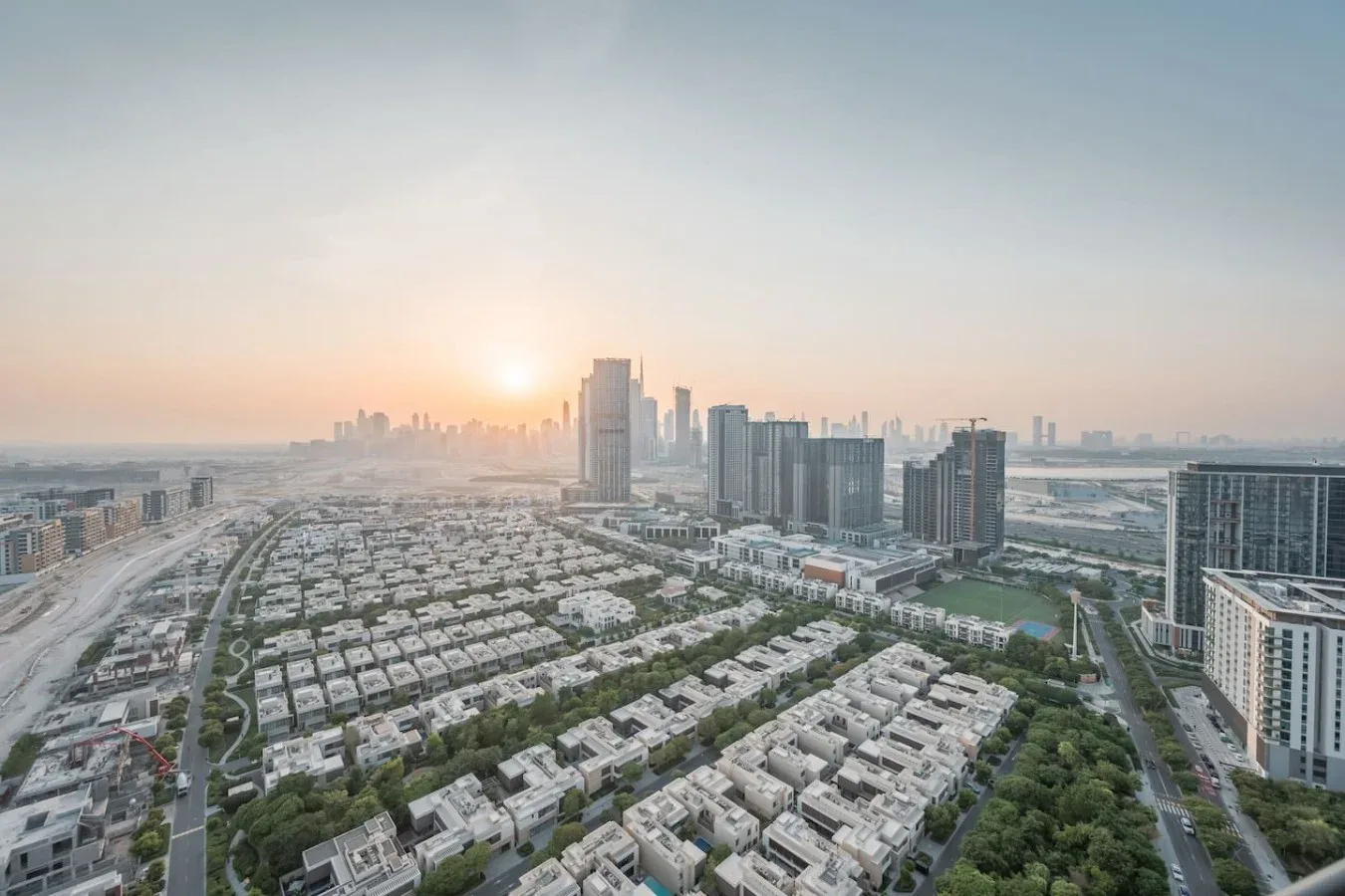 Vista aérea de un barrio residencial y edificios altos al atardecer.