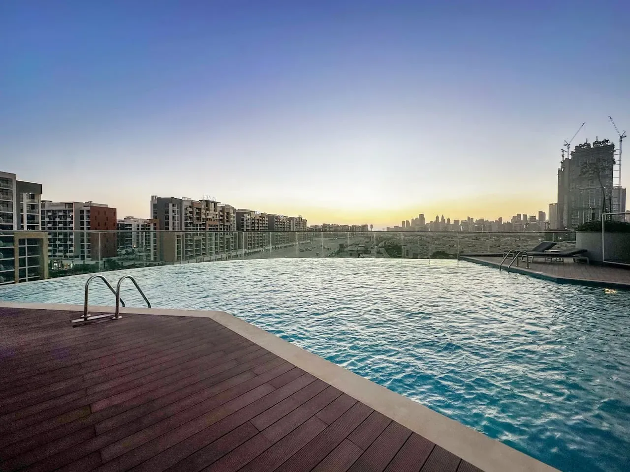 Una piscina en la azotea ofrece vistas de edificios cercanos al atardecer.