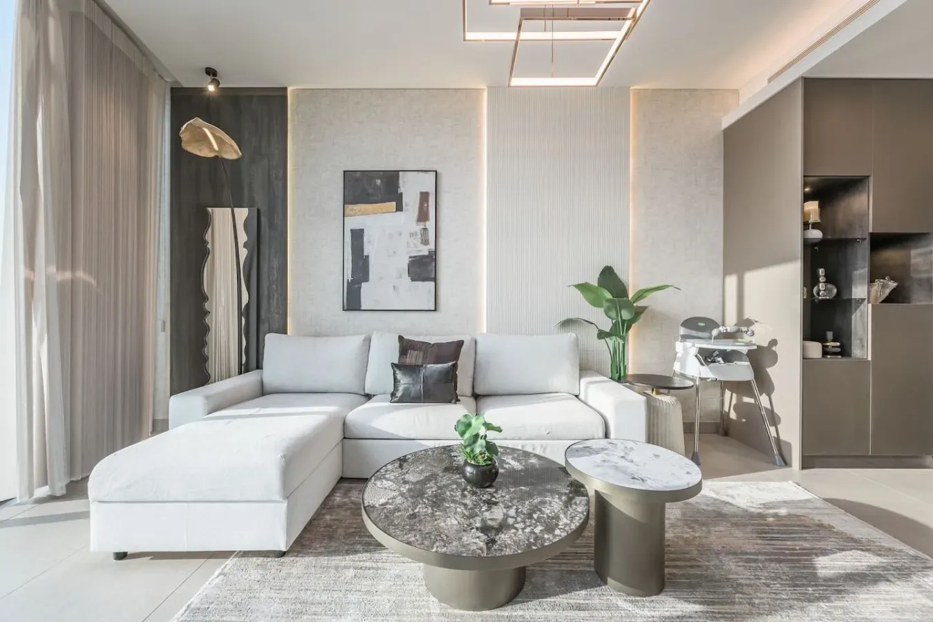 Una luminosa sala de estar con asientos blancos, una mesa de centro y un comedor.