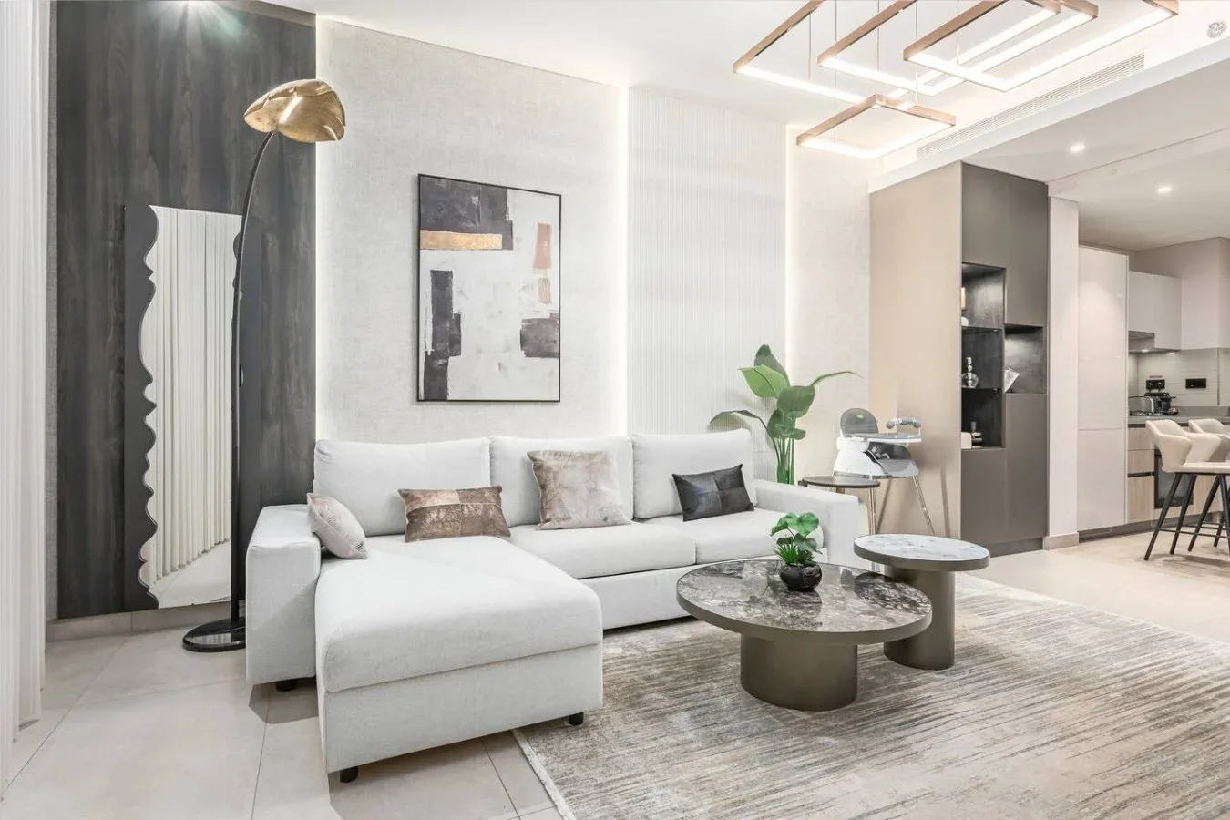 Una sala de estar moderna y luminosa con un sofá seccional y mesas de centro redondas.