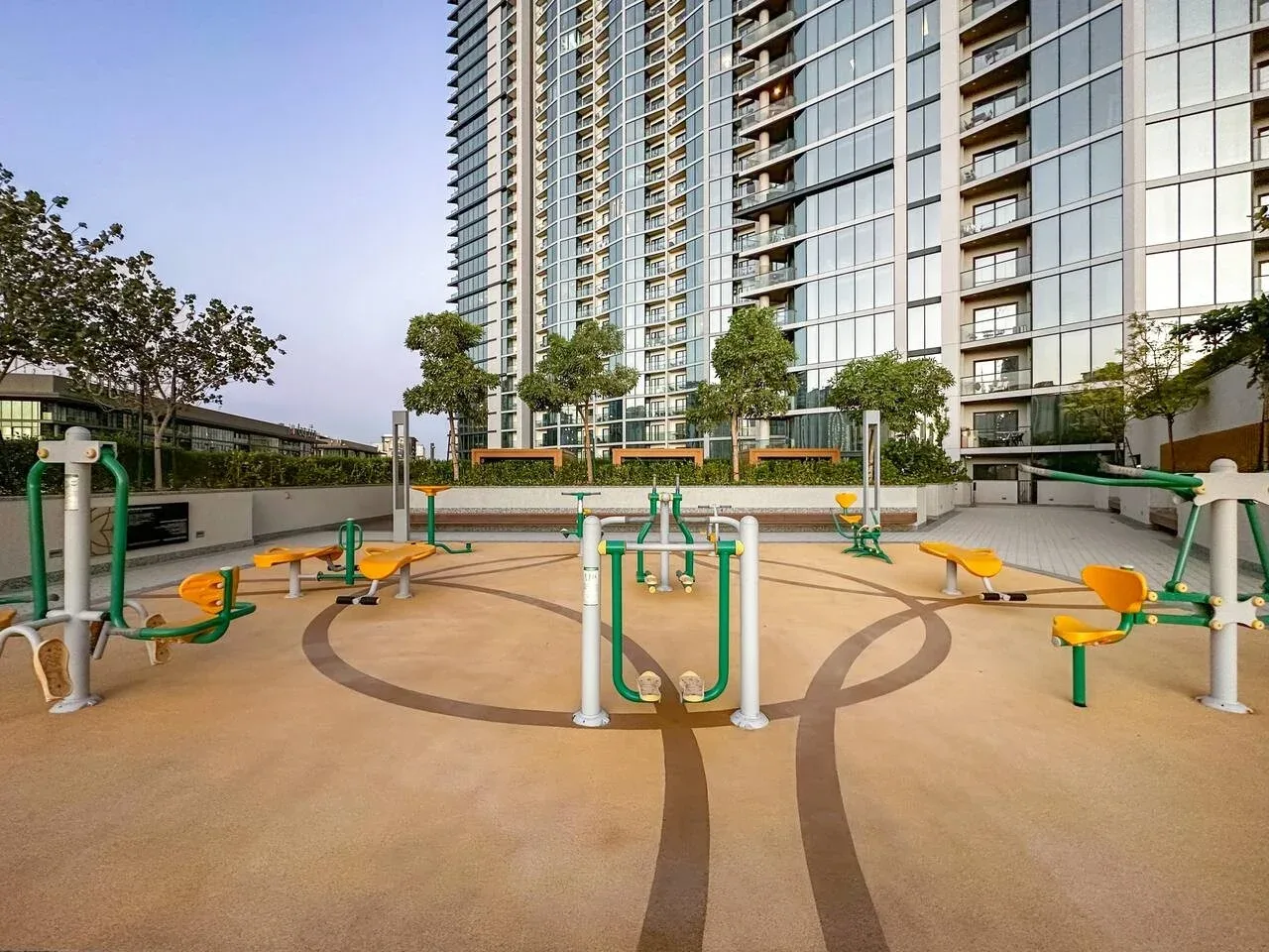 Una zona de ejercicio al aire libre con equipos frente a edificios residenciales altos.
