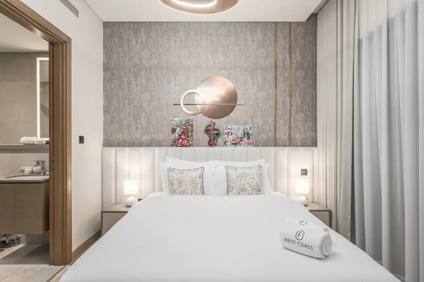 Un dormitorio con una cama bien tendida y arte abstracto en la pared.