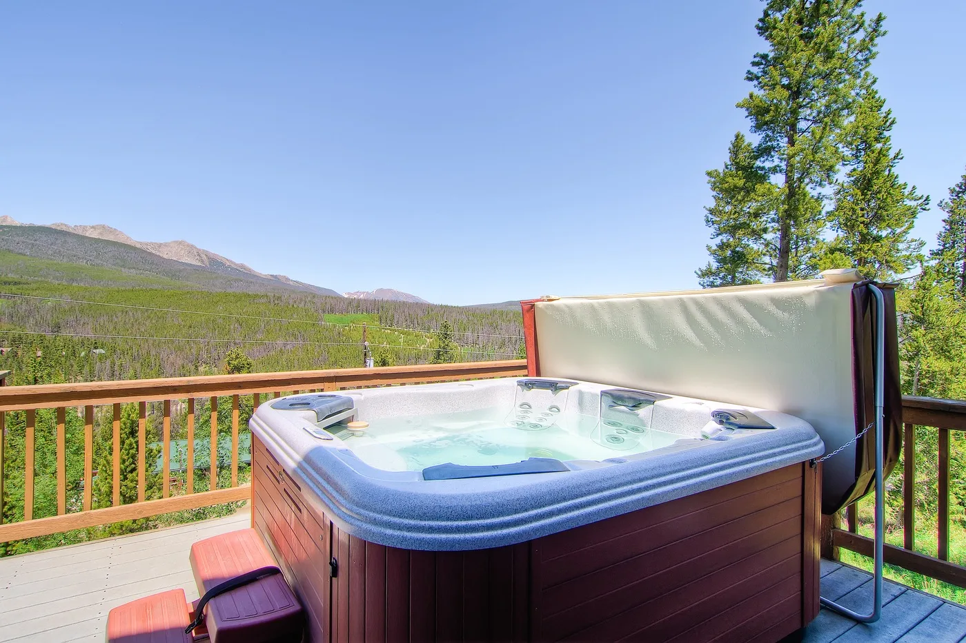 An outdoor hot tub sits on a deck overlooking a mountain landscape.
