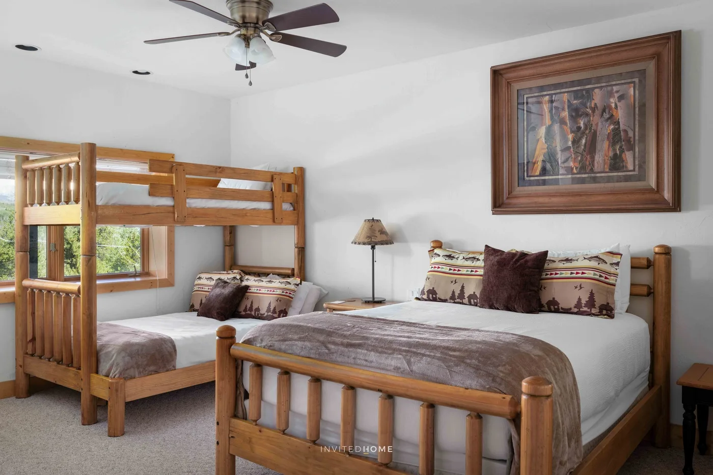 Bedroom with wooden bunk beds, patterned bedding, and framed wall art.