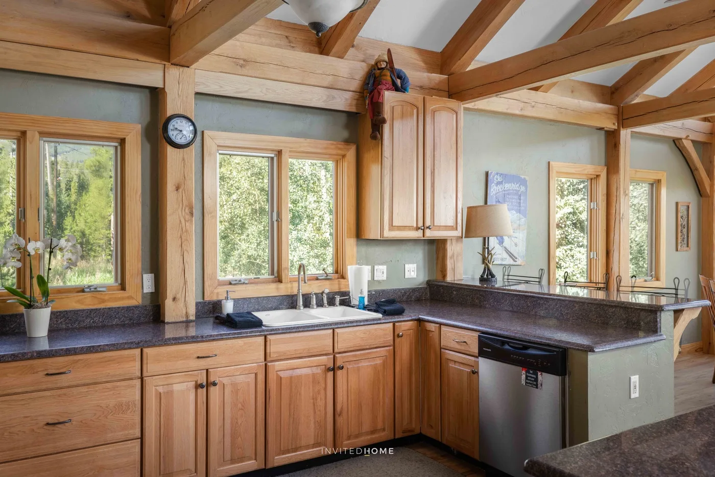 A kitchen with wooden cabinets, dark countertops, and large windows.