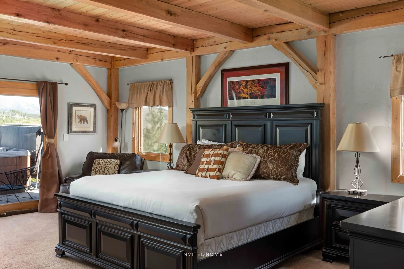 A bedroom with a large bed beneath exposed wooden ceiling beams.