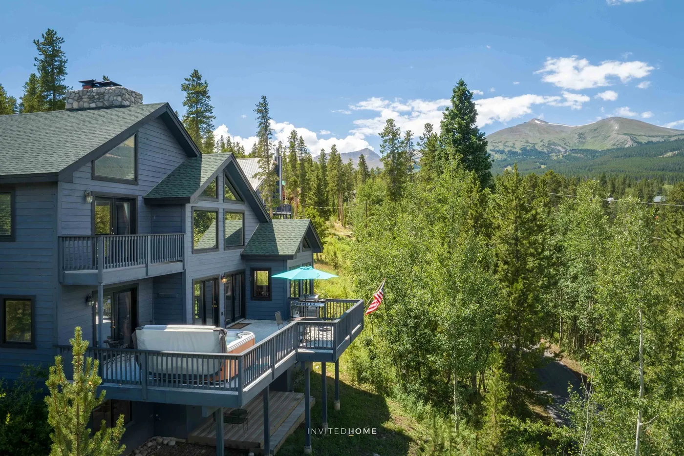 Mountain cabin with a raised deck overlooking a forested landscape.