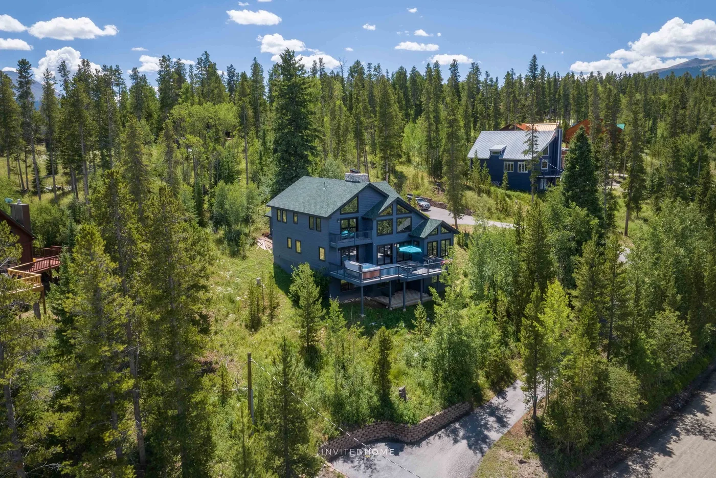 Aerial view of a house among trees, with a second house nearby.
