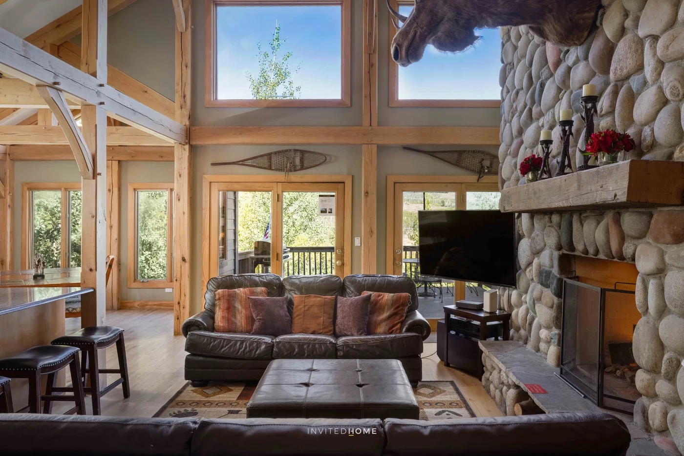 A spacious living room with a sofa facing a stone fireplace and television.