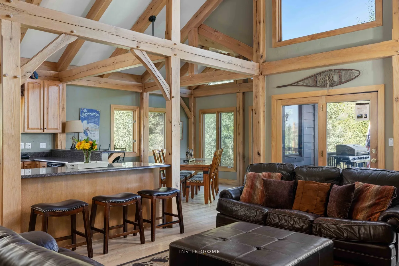 An open-plan living room and kitchen with exposed timber beams and a dining area.