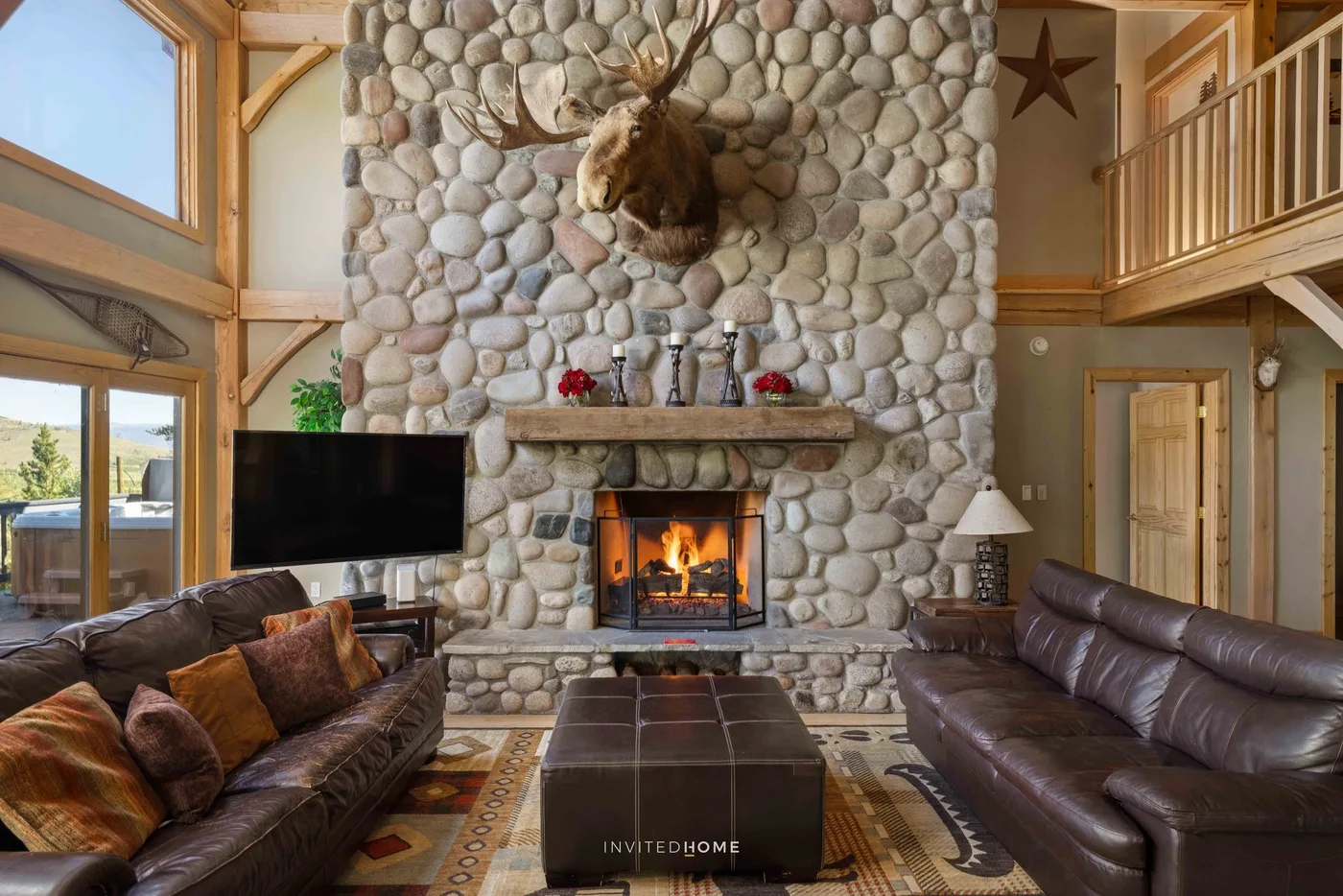 A spacious living room with a stone fireplace and seating.