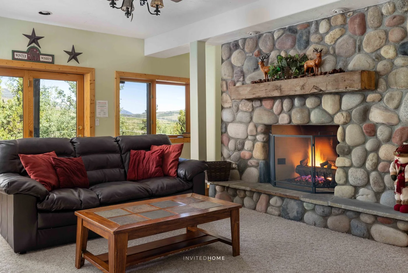 A living room with dark seating, a wooden coffee table, and a stone fireplace.