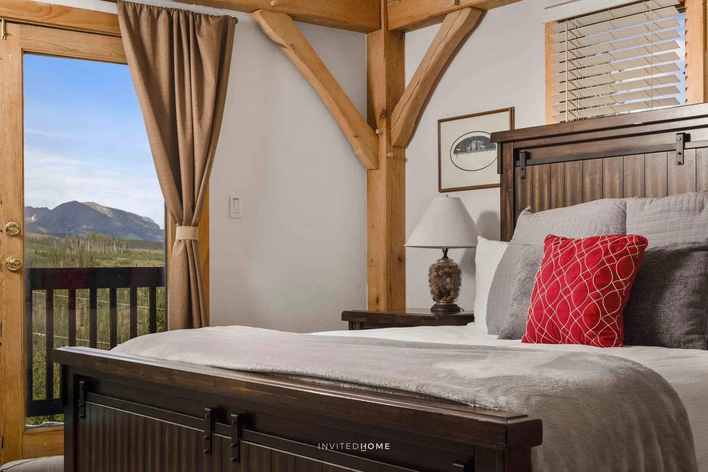 A bedroom with a large bed beside a window overlooking a mountain landscape.