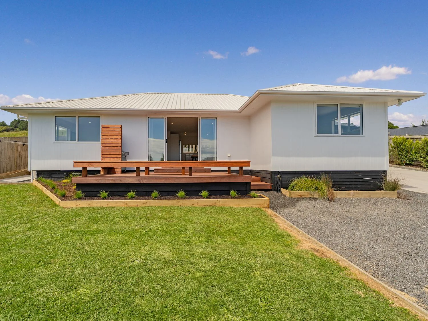 A modern single-story house with a lawn and a raised wooden deck.