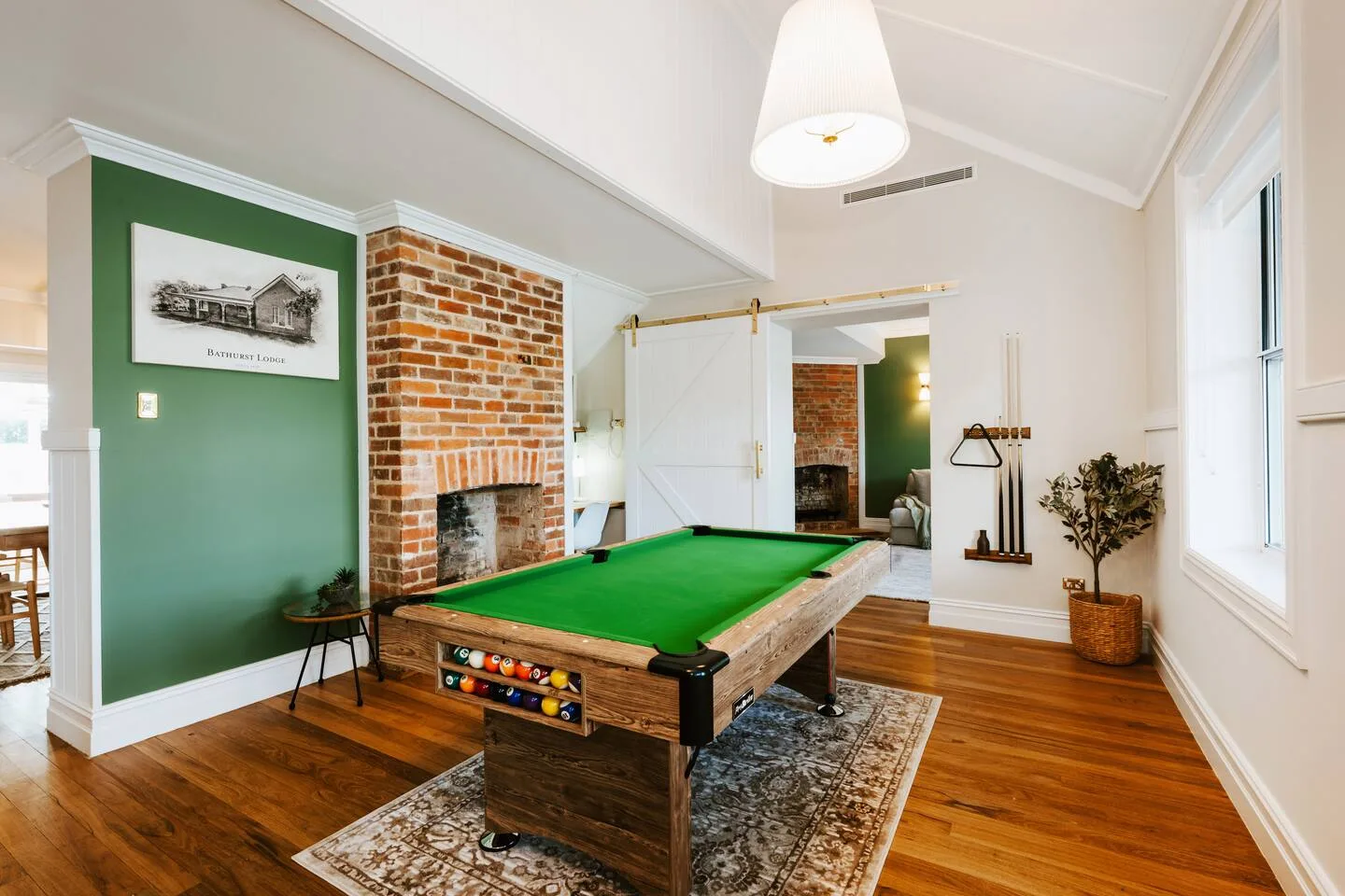 A billiards table sits in a bright room with exposed brick walls.