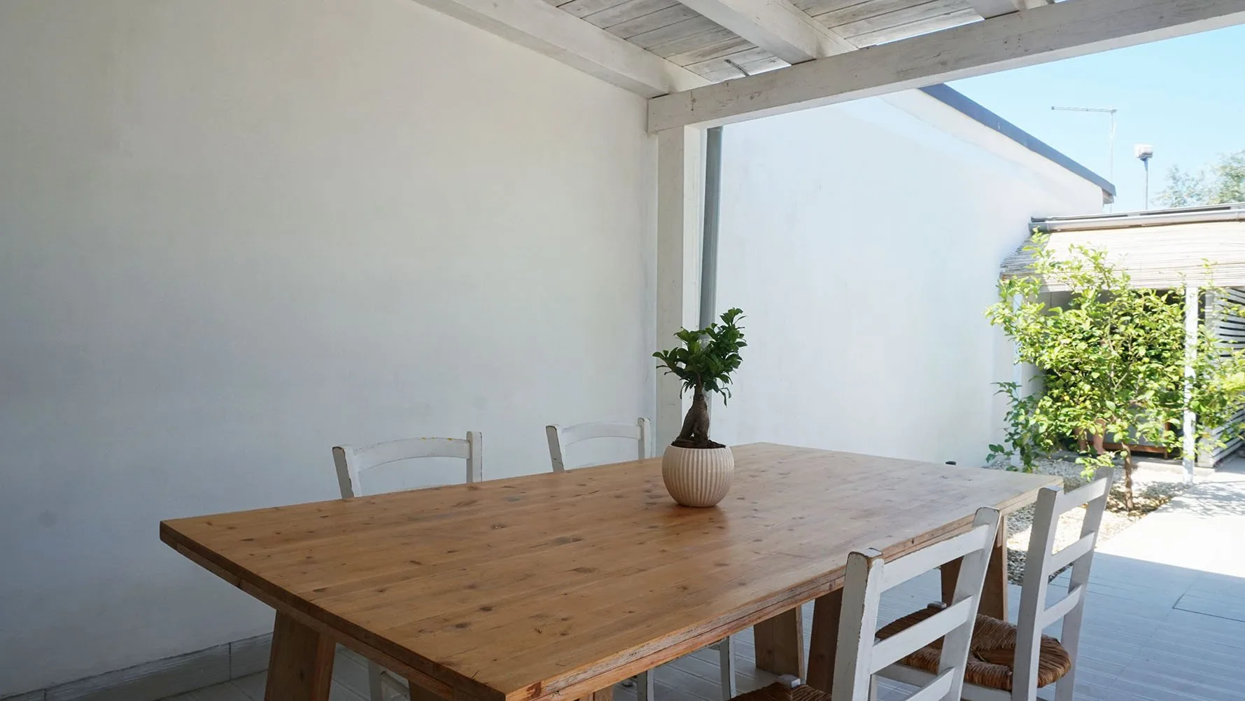 Comedor exterior cubierto con una mesa de madera y asientos.