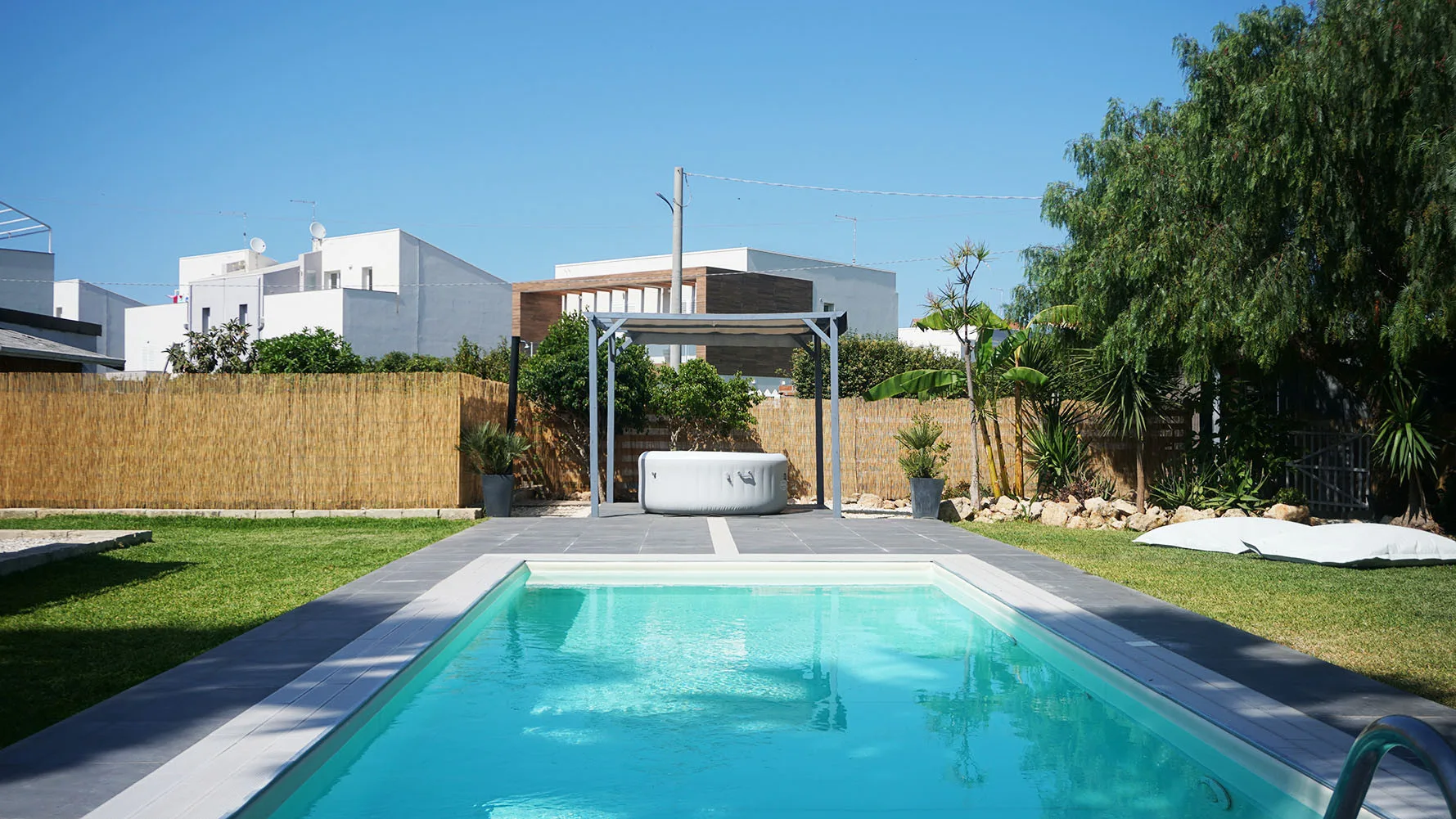 Una piscina al aire libre con un jacuzzi de estructura metálica al fondo.