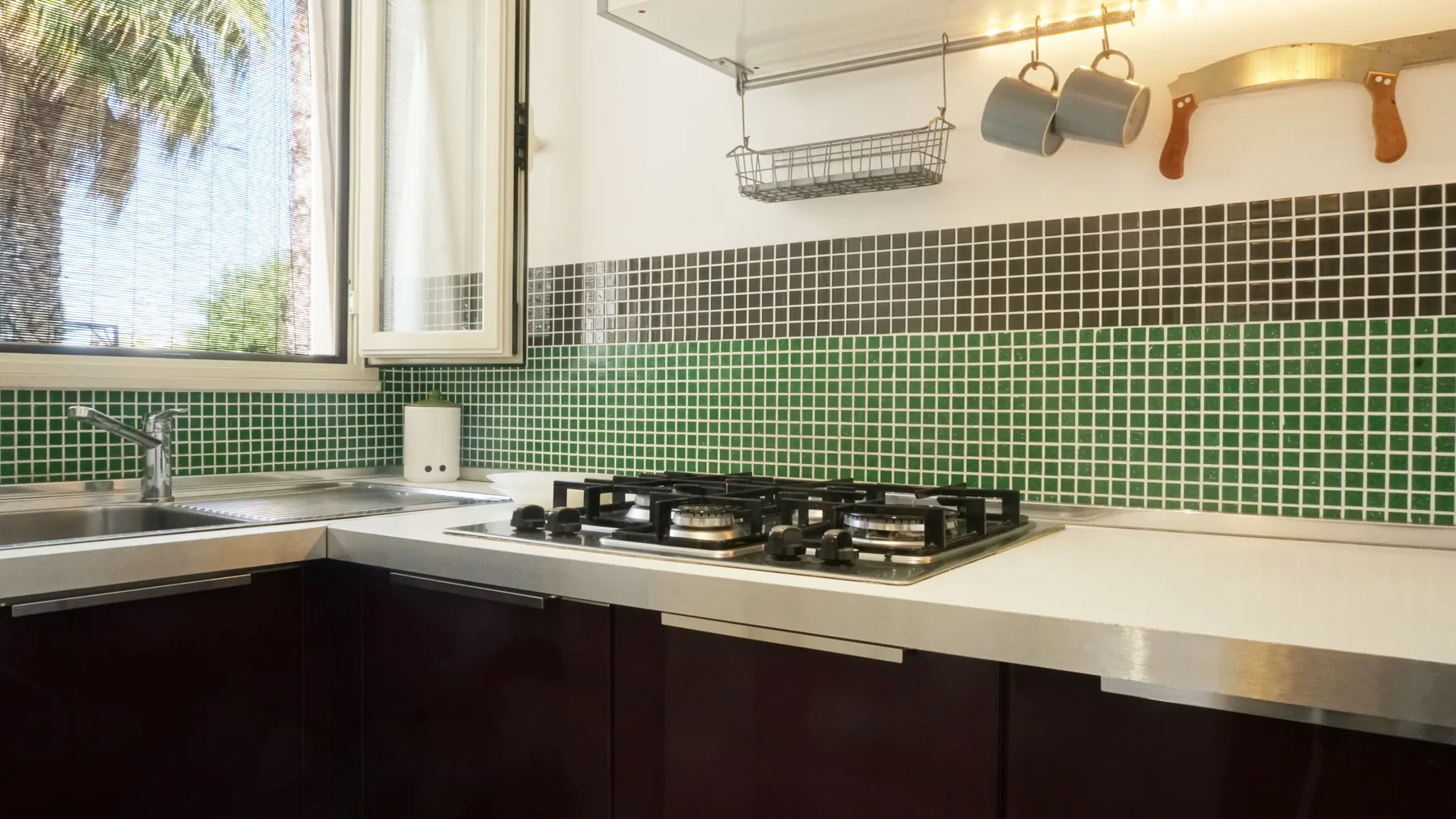 Una cocina con una estufa de gas, azulejos en la pared y una ventana.