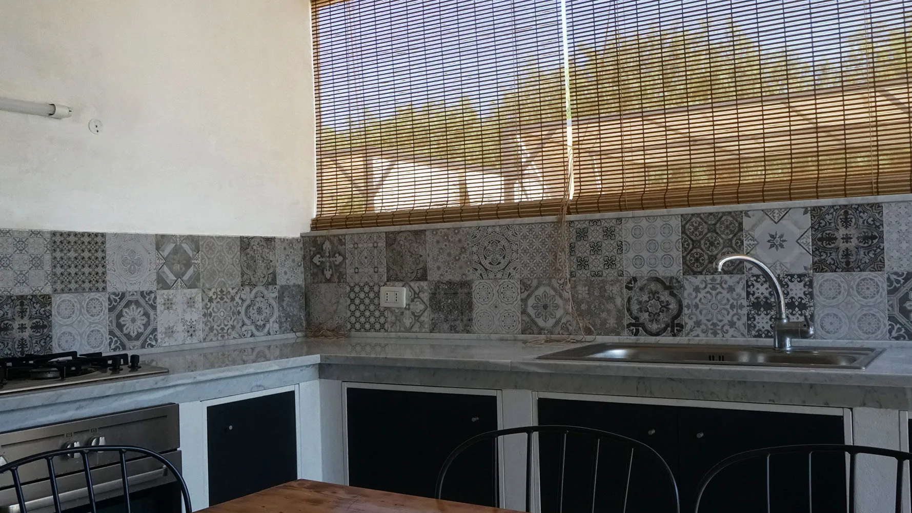 Una cocina con salpicadero de azulejos, encimera y fregadero bajo una ventana.
