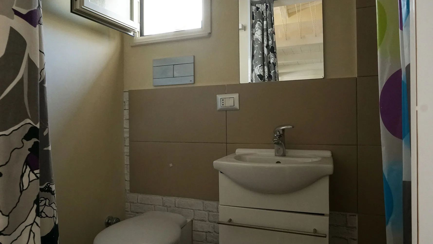 Un lavabo y un espejo están frente a una pared revestida de azulejos.