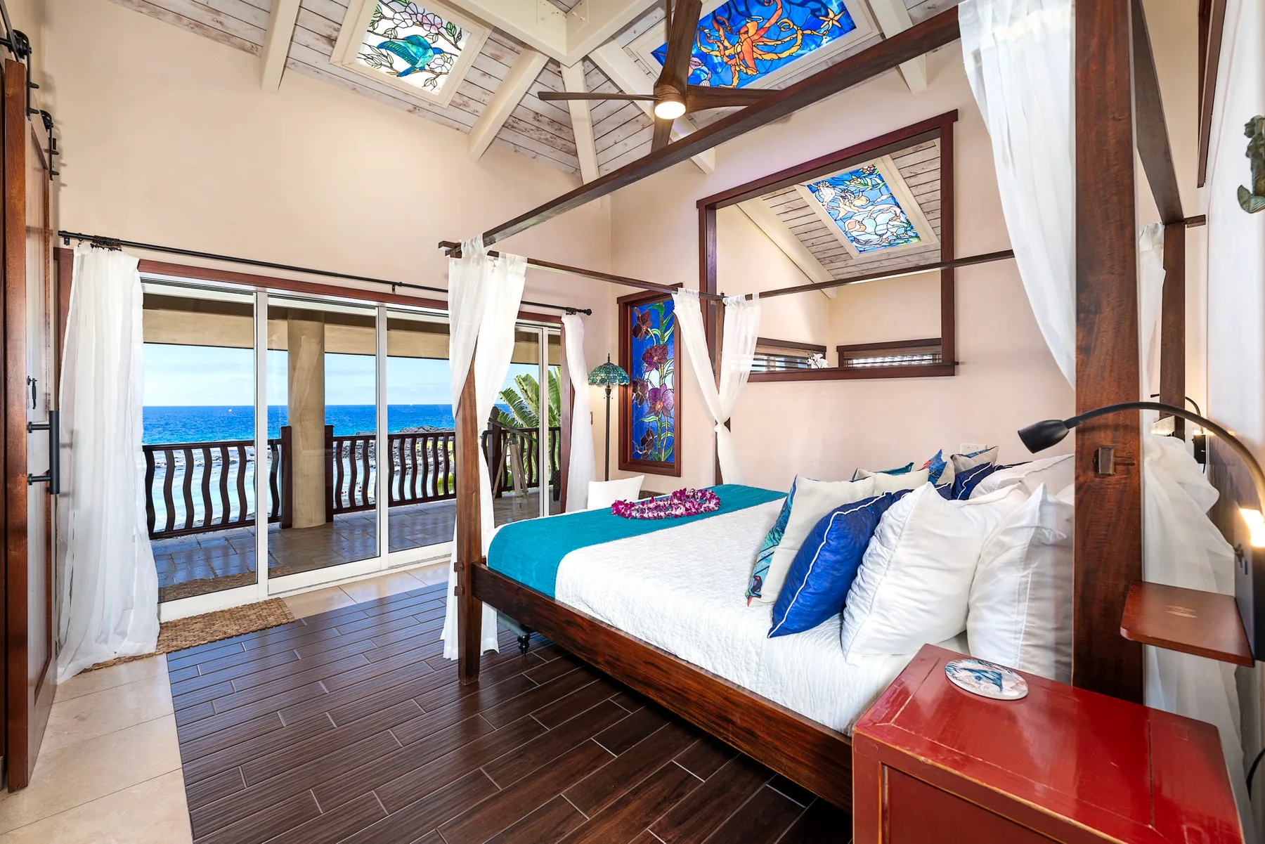 A bedroom with a large bed, sliding glass doors, and an ocean view.