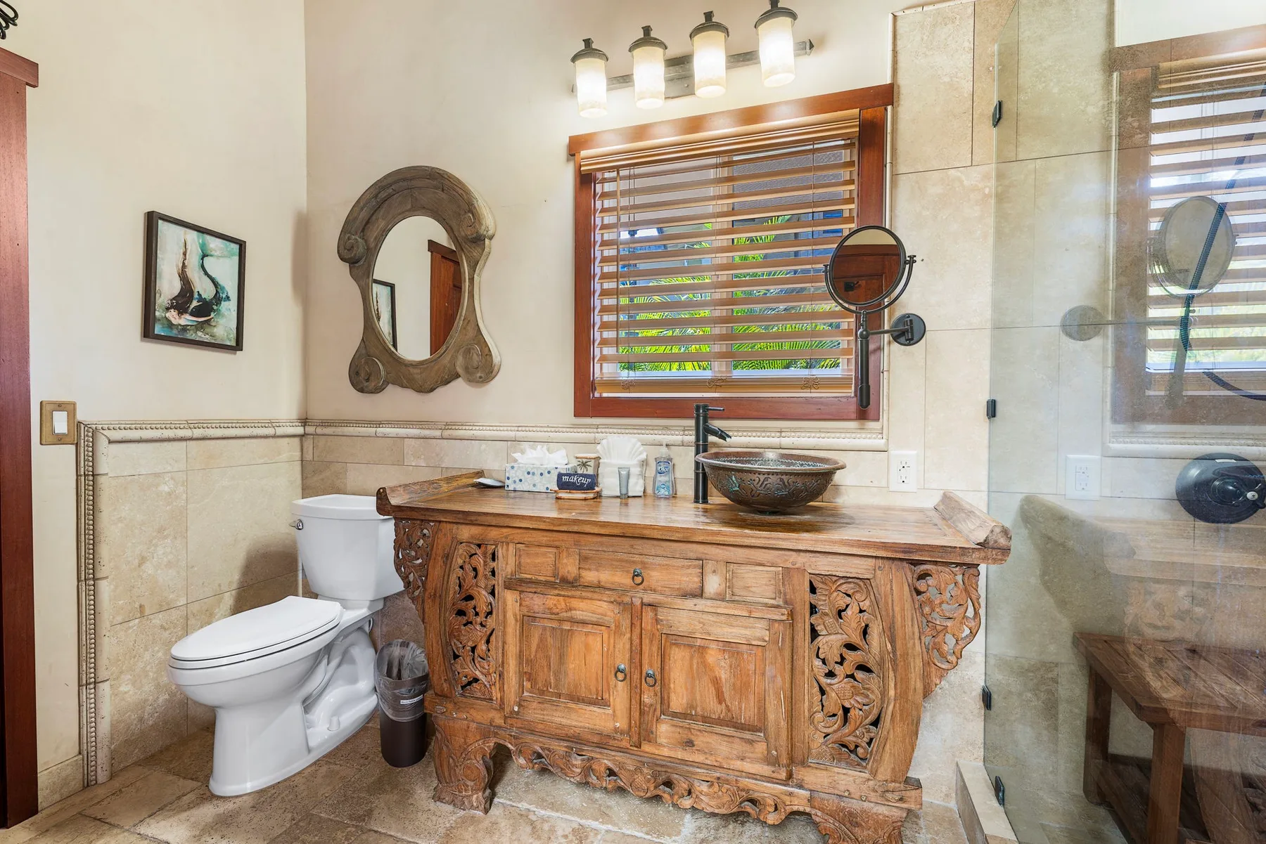 A bathroom with an ornate wooden vanity, sink, and toilet.