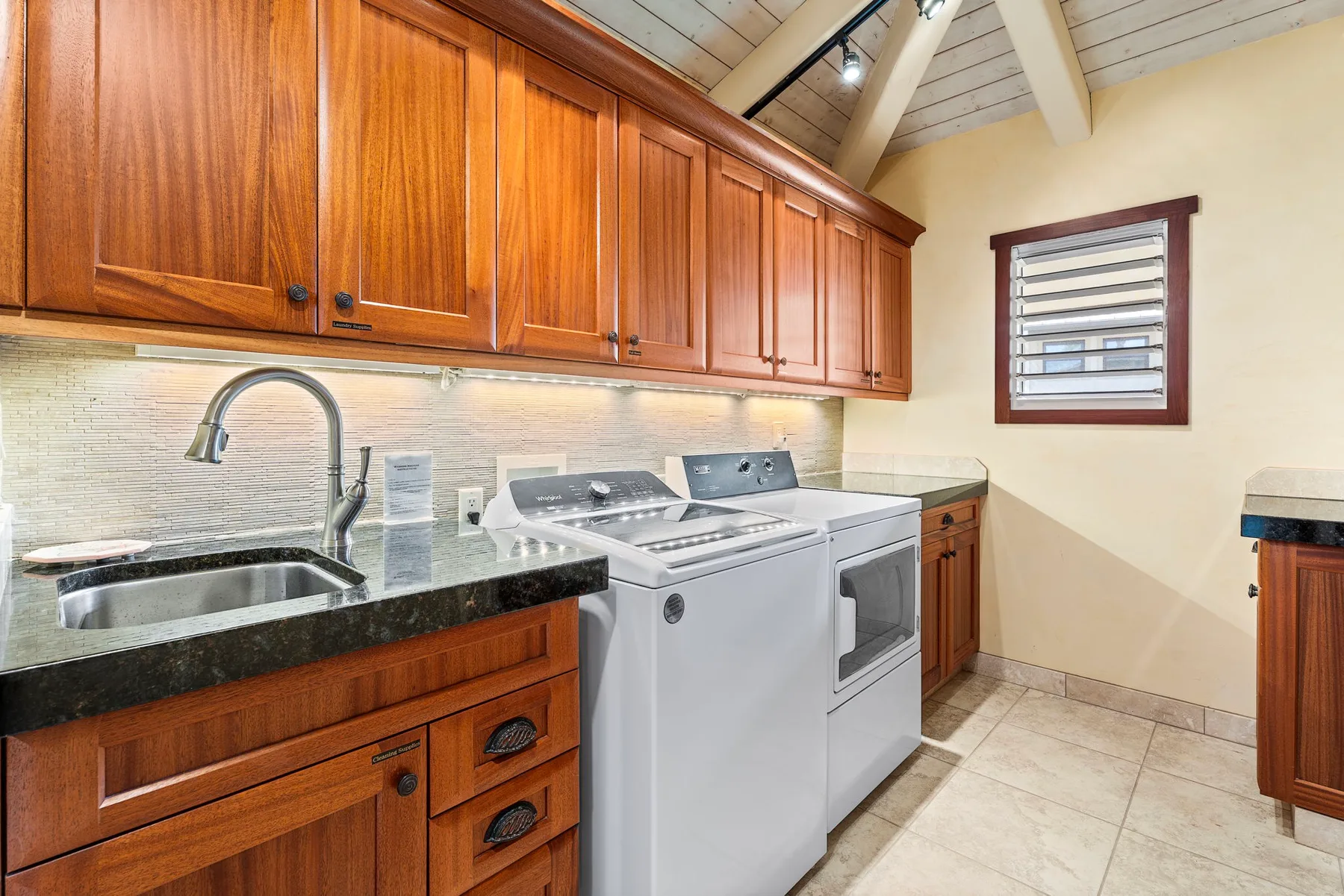 A kitchen with wooden cabinets, a sink, and laundry appliances.