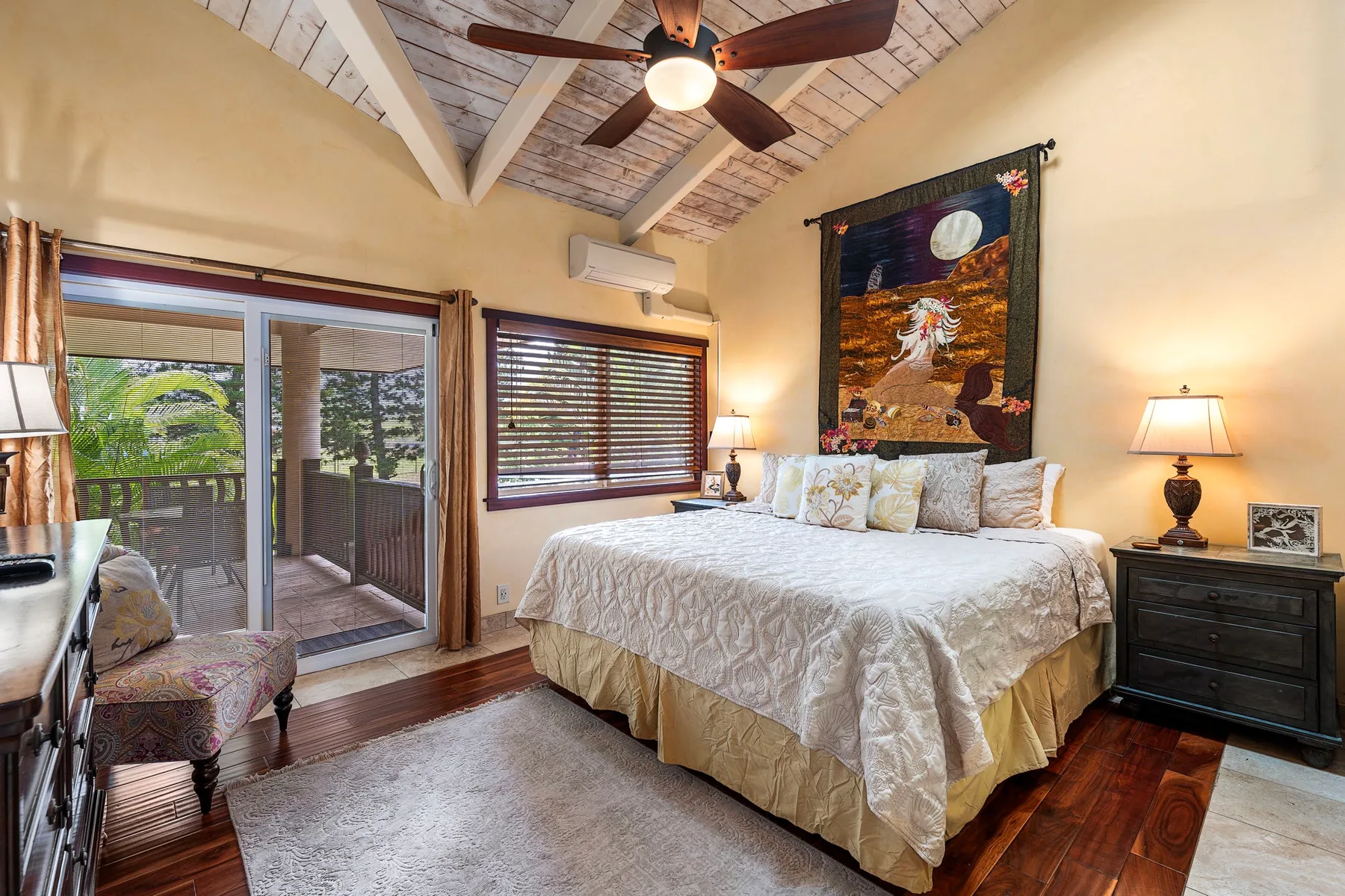 A bedroom with a large bed, ceiling fan, and sliding glass doors.