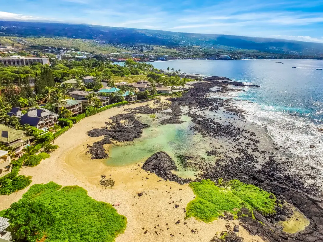 Aerial view of a sandy beach with rocky shoreline and turquoise water.