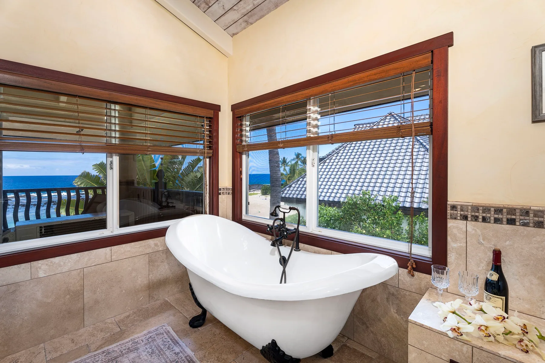 A freestanding bathtub sits beside large windows overlooking the ocean.