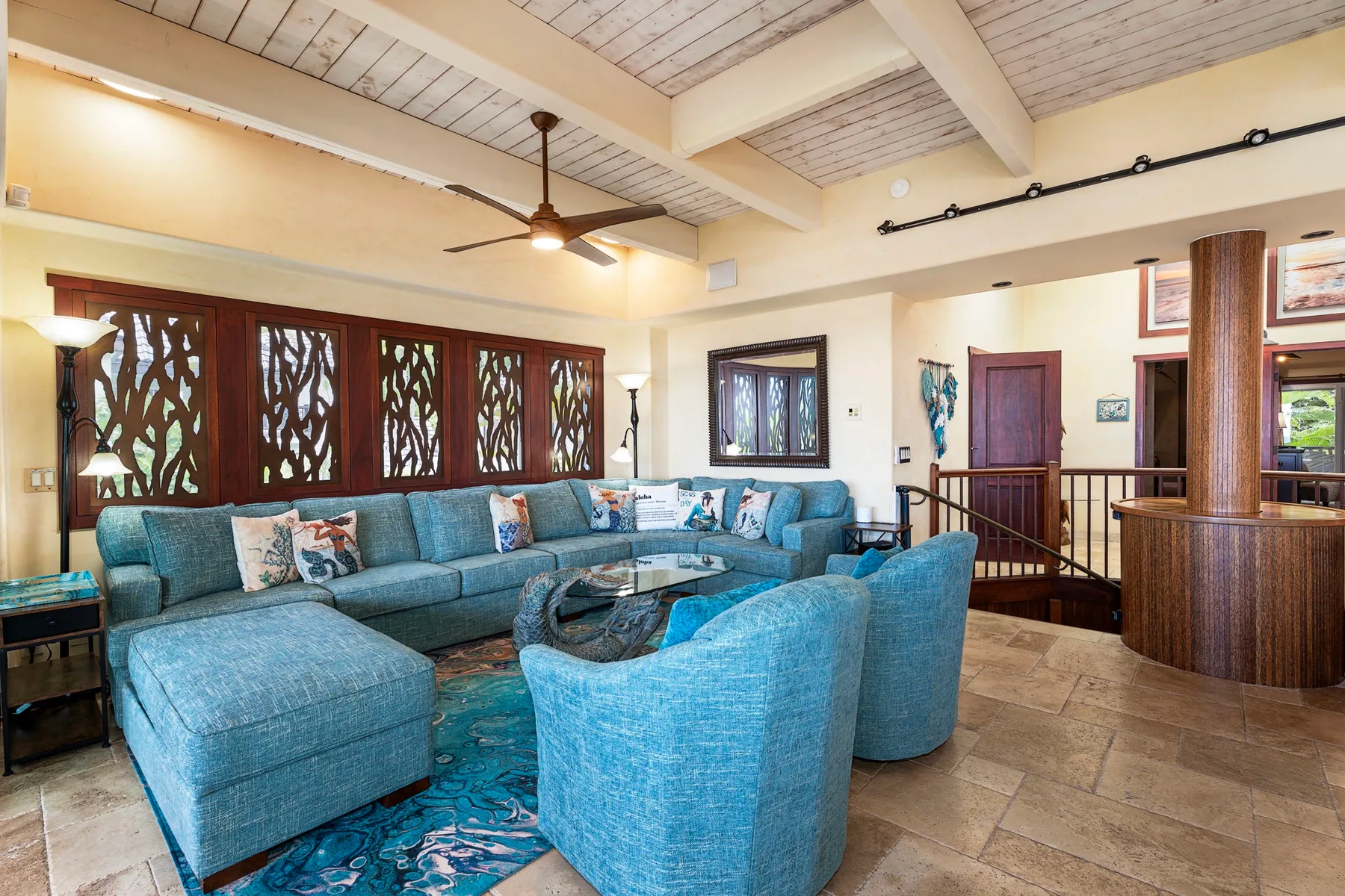 A spacious living room with blue seating, a coffee table, and decorative window screens.