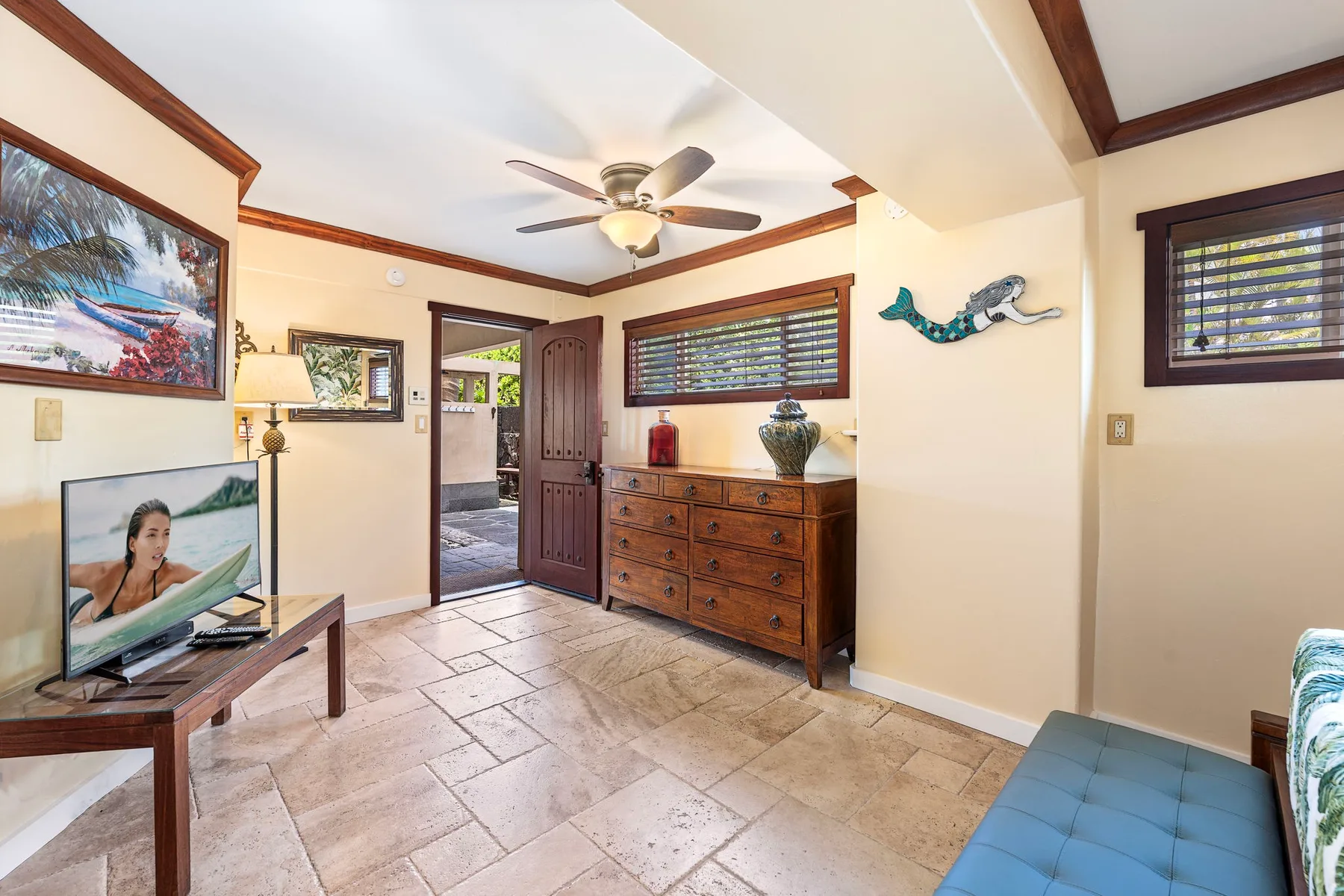 A bedroom with a wooden dresser, ceiling fan, and an open doorway.