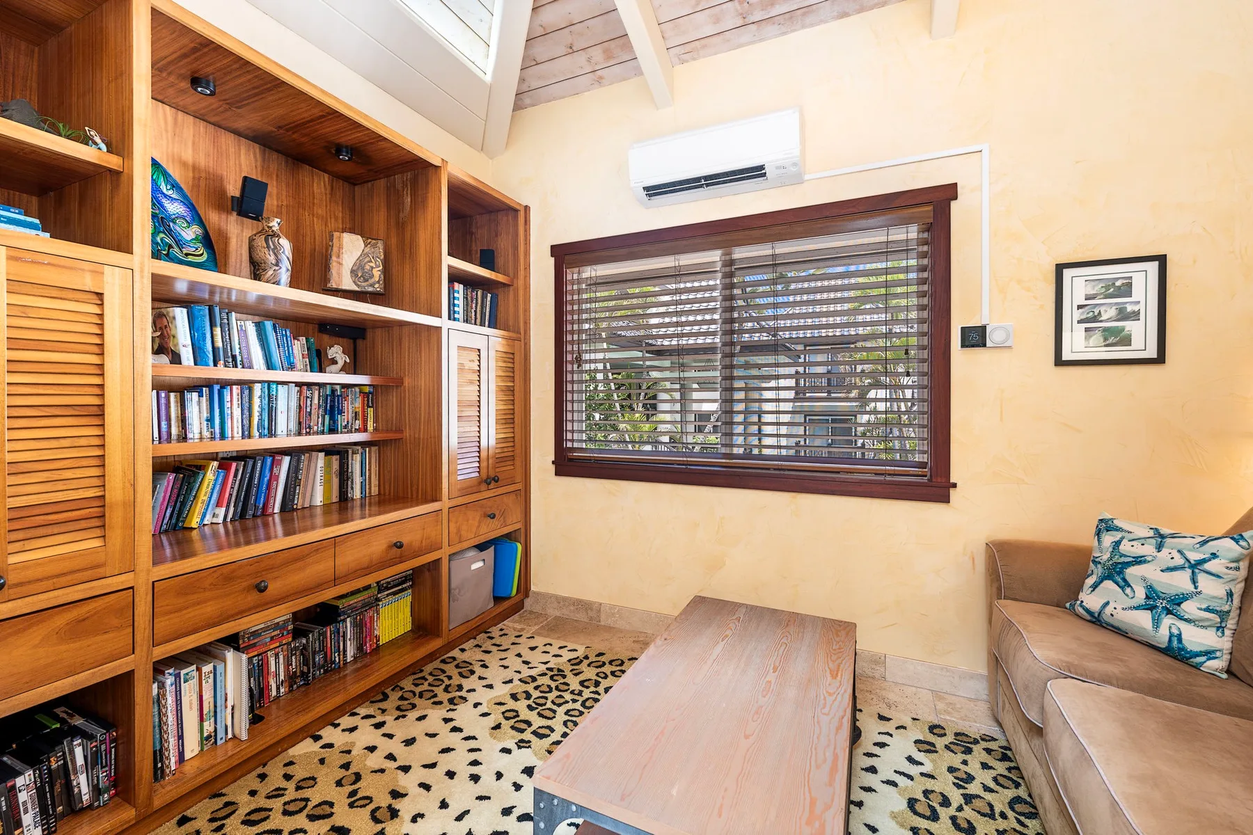 A living room with wooden bookshelves, a window, and seating.