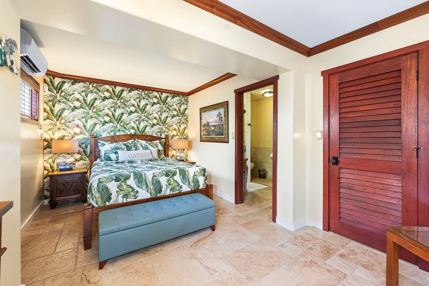 A bedroom with a patterned bed, bedside tables, and a blue bench.