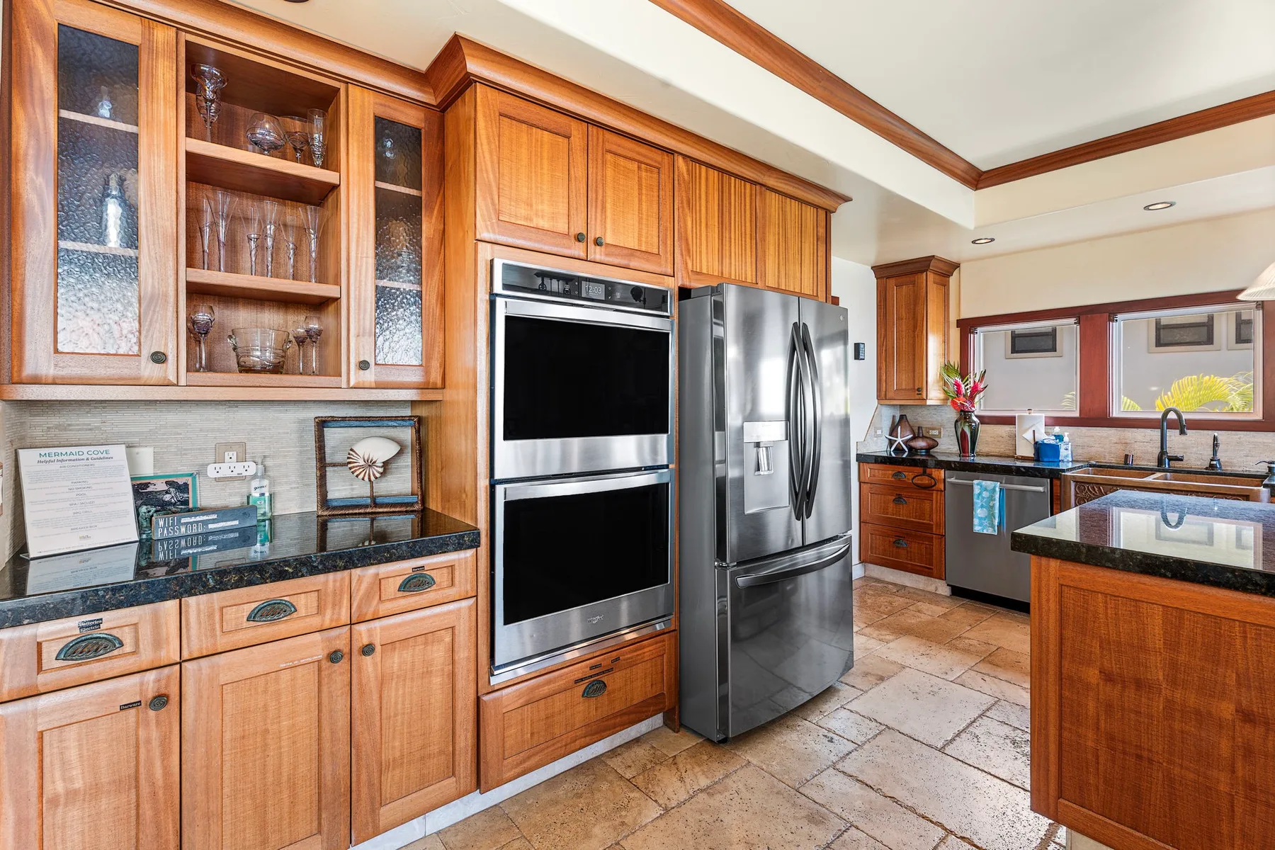 A kitchen with wooden cabinetry, built-in ovens, and a stainless-steel refrigerator.