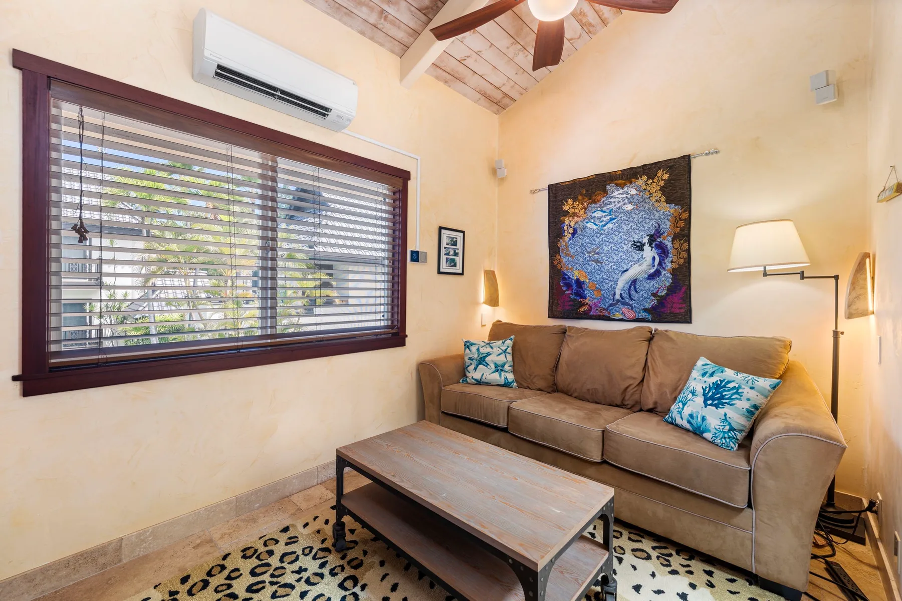 A living room with a sofa, coffee table, and large window with blinds.