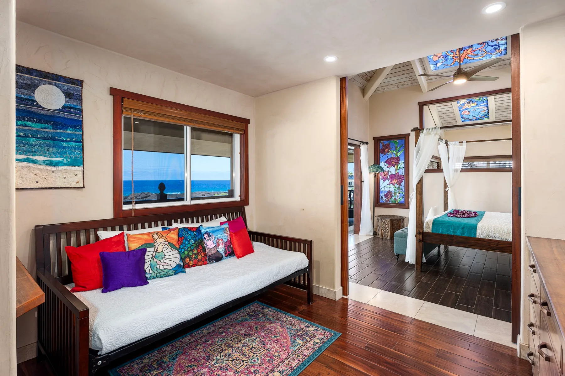 A bedroom sitting area with a daybed beneath a window overlooking the sea.