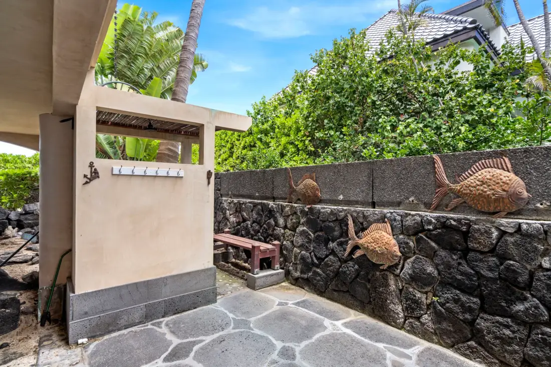 An outdoor entry area with a stone path and fish sculptures along the wall.