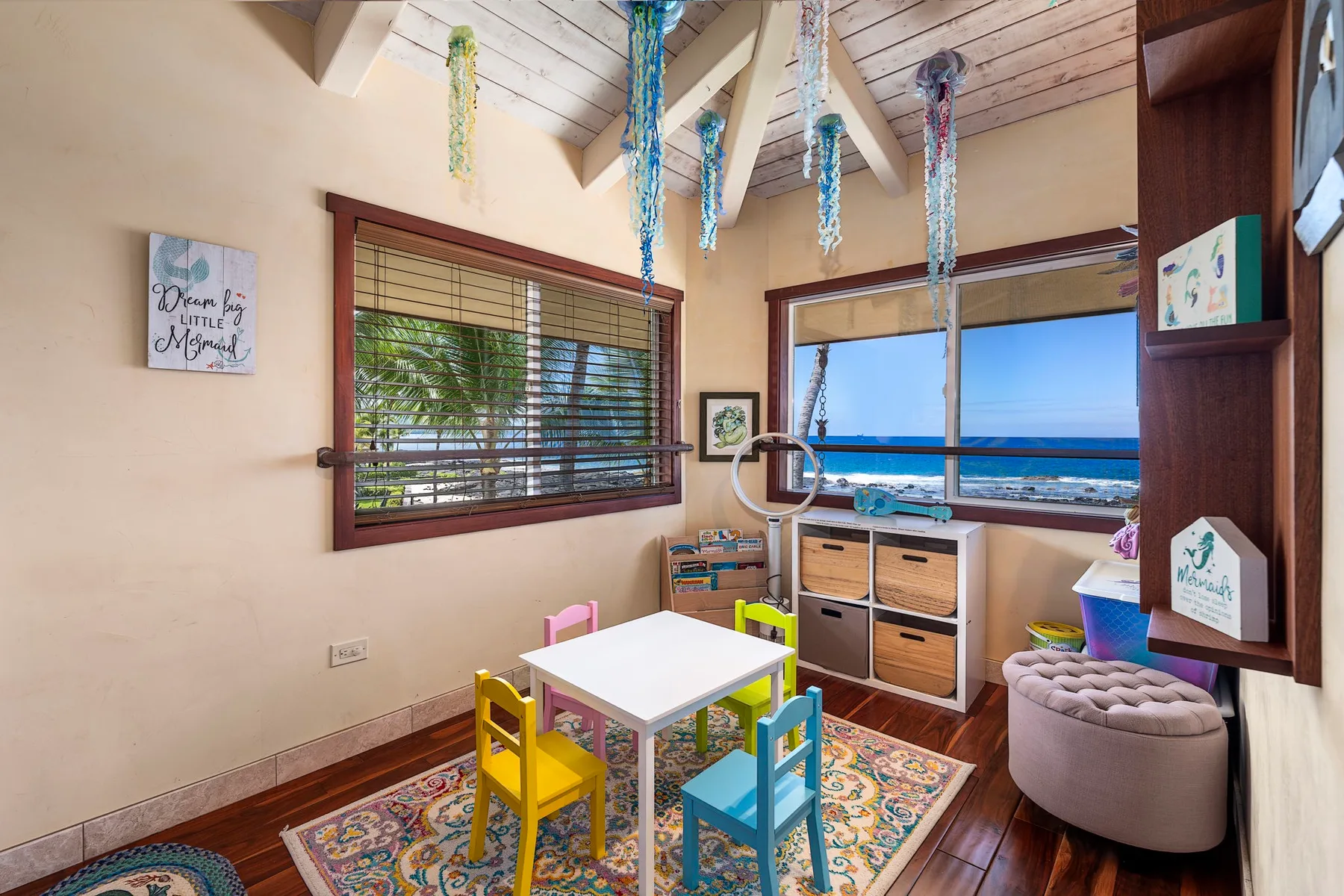 A colorful dining nook with a small table beside windows overlooking the ocean.