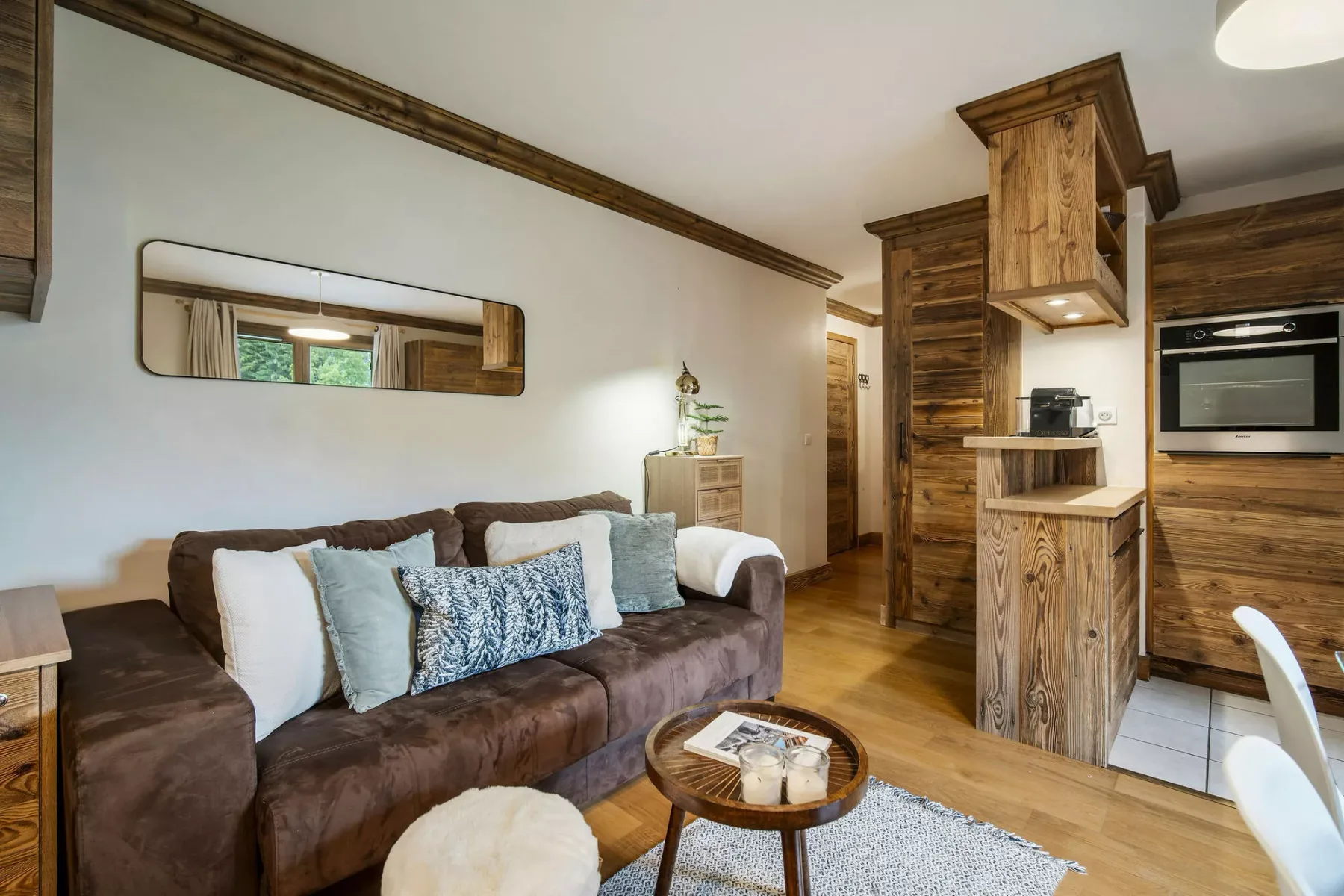 A living room with a brown sofa and a compact kitchen area.