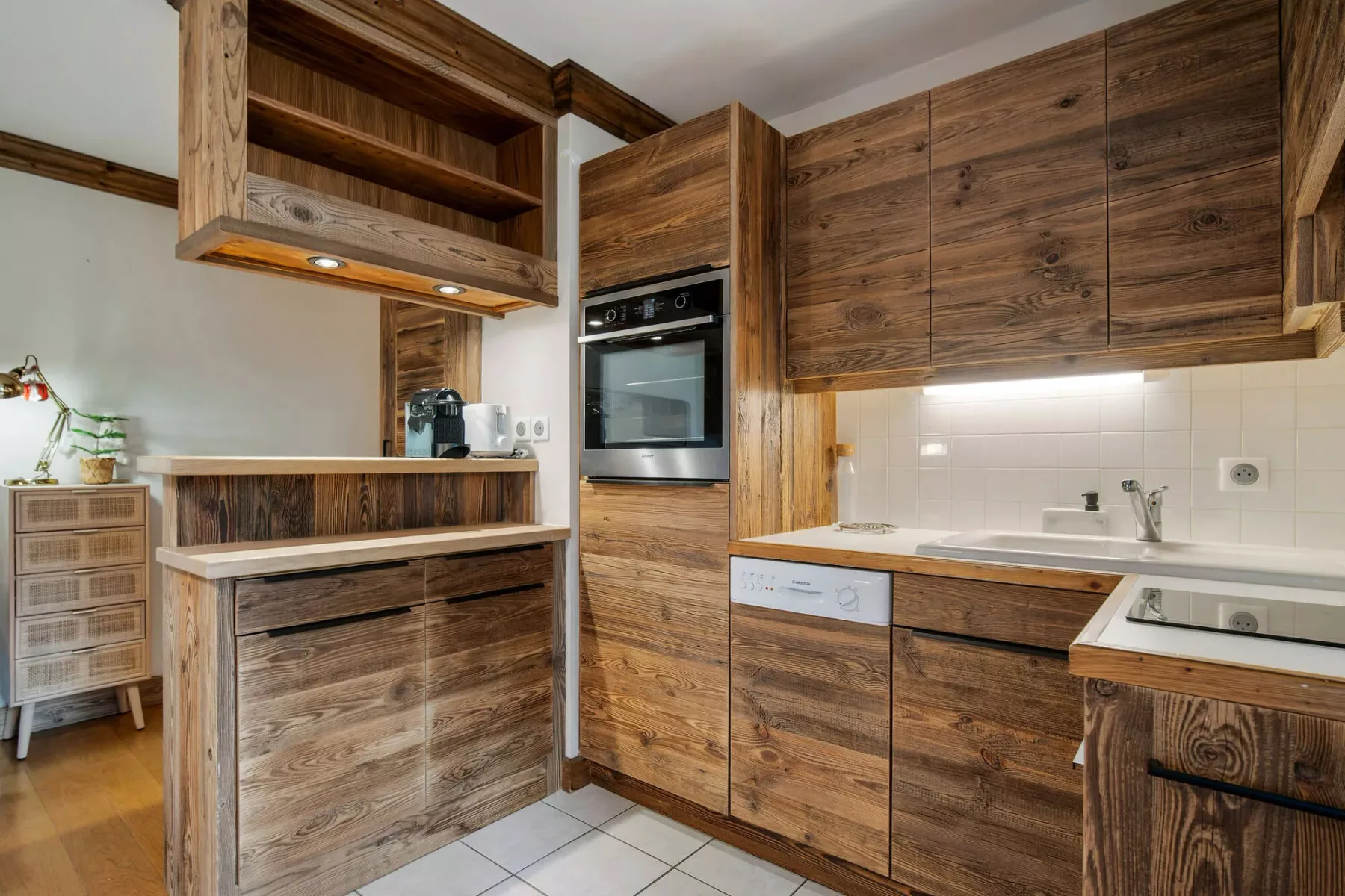 Una cocina con acabados de madera, electrodomésticos integrados y suelo de baldosas.