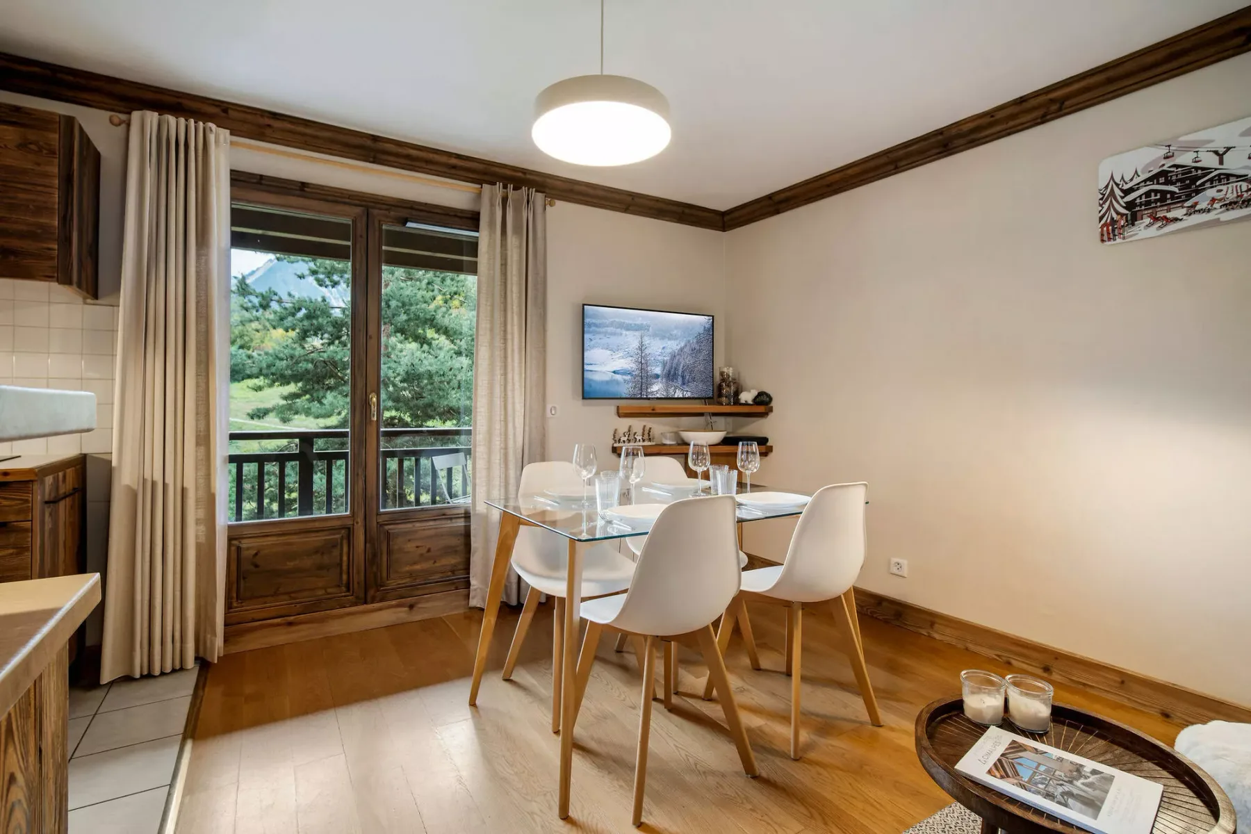 Dining area with a table and chairs beside glass doors opening onto greenery.