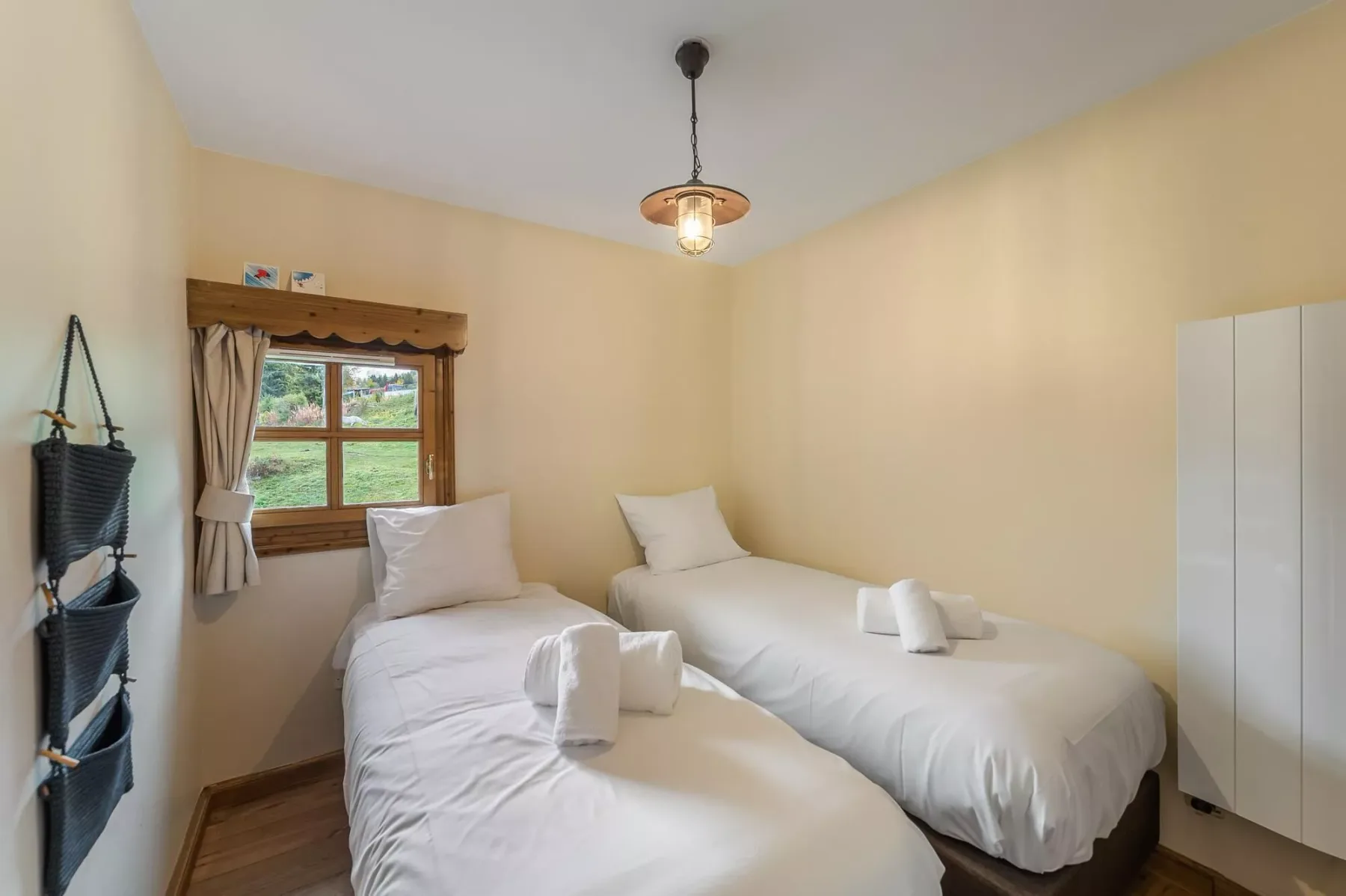 Un dormitorio con dos camas, una ventana y un armario.