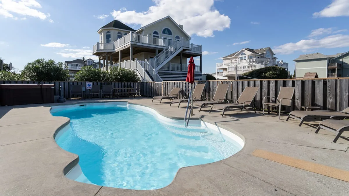 Una piscina al aire libre con asientos y casas al fondo.