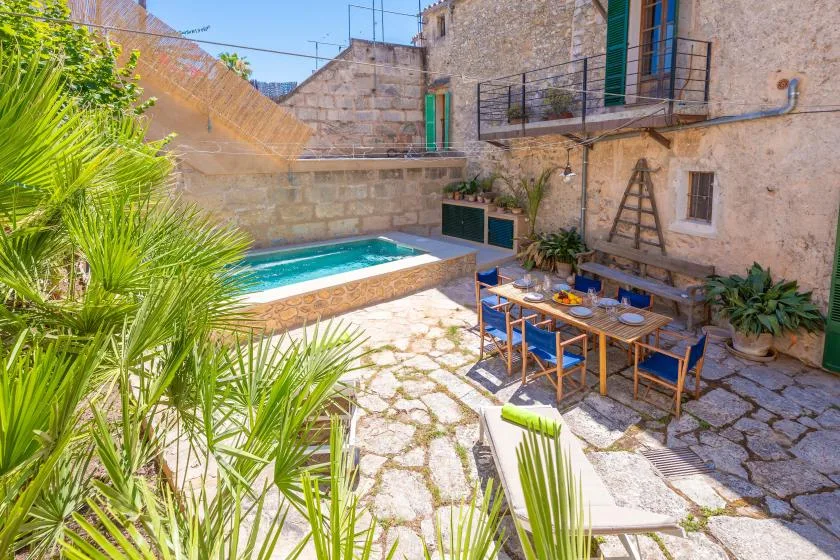 Un patio con una piscina pequeña y una mesa de comedor al aire libre.