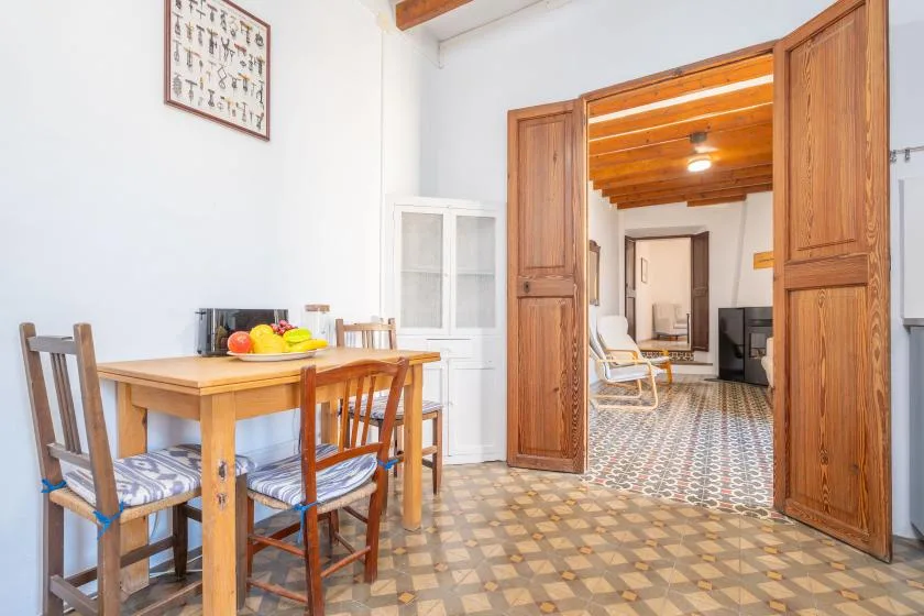 Un comedor con mesa y sillas de madera se abre a una sala de estar.