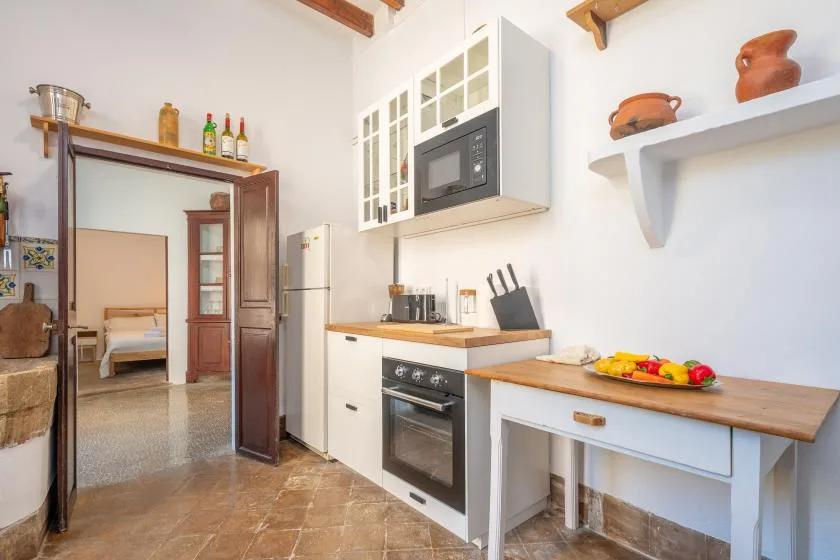 Una cocina luminosa con armarios blancos, horno empotrado y encimera de madera.