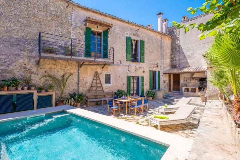 Un patio de piedra con piscina, asientos al aire libre y una mesa de comedor.